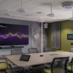 Modern meeting room with ceiling microphones, speakers, acoustic panels, and display technology for professional AV audio solutions.